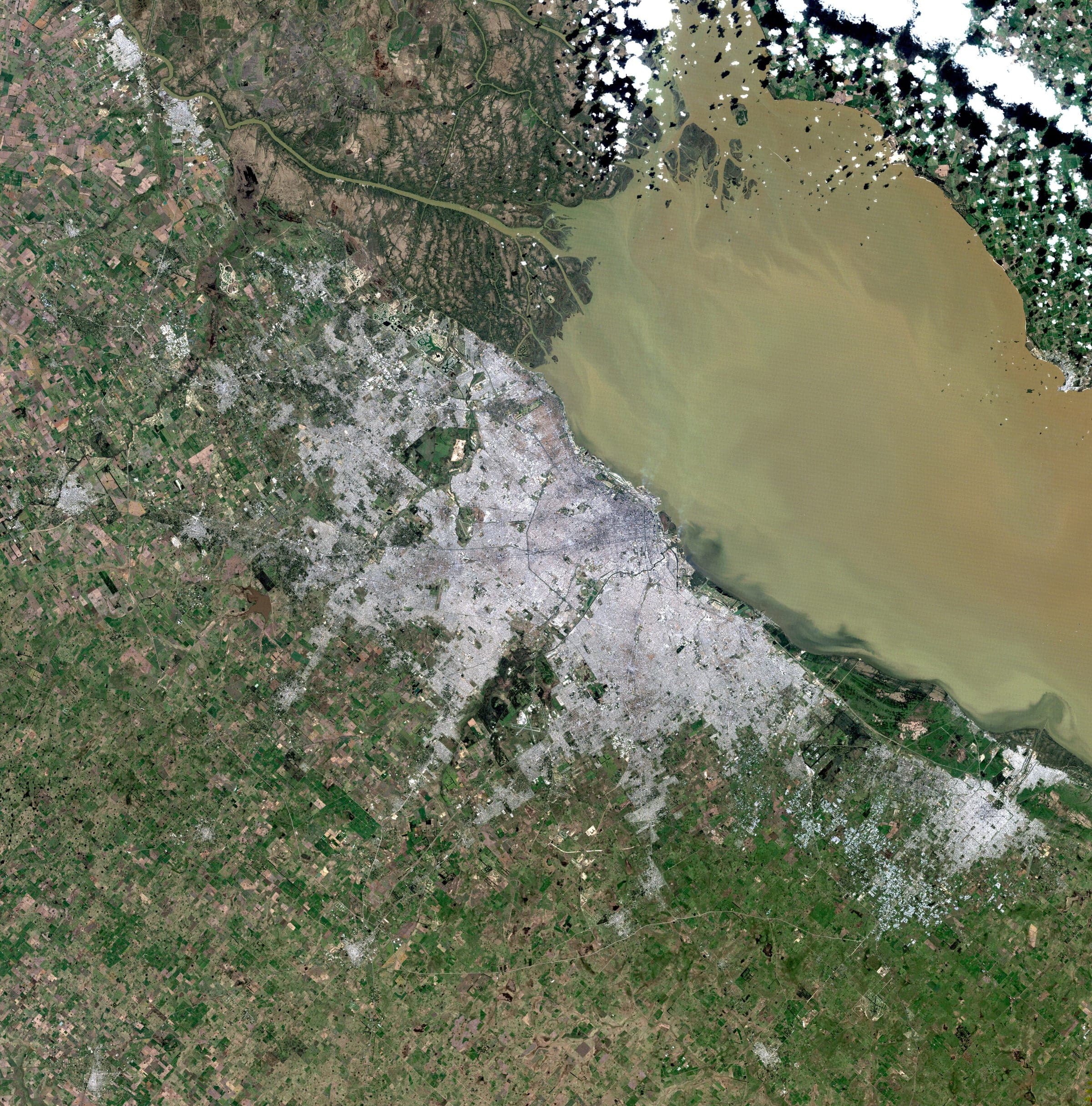 Buenos Aires on the southern bank of the Río de la Plata, the estuary carrying enough suspended sediment to turn the water opaque brown across the top of the frame. Landsat frame, 30 metres per pixel.