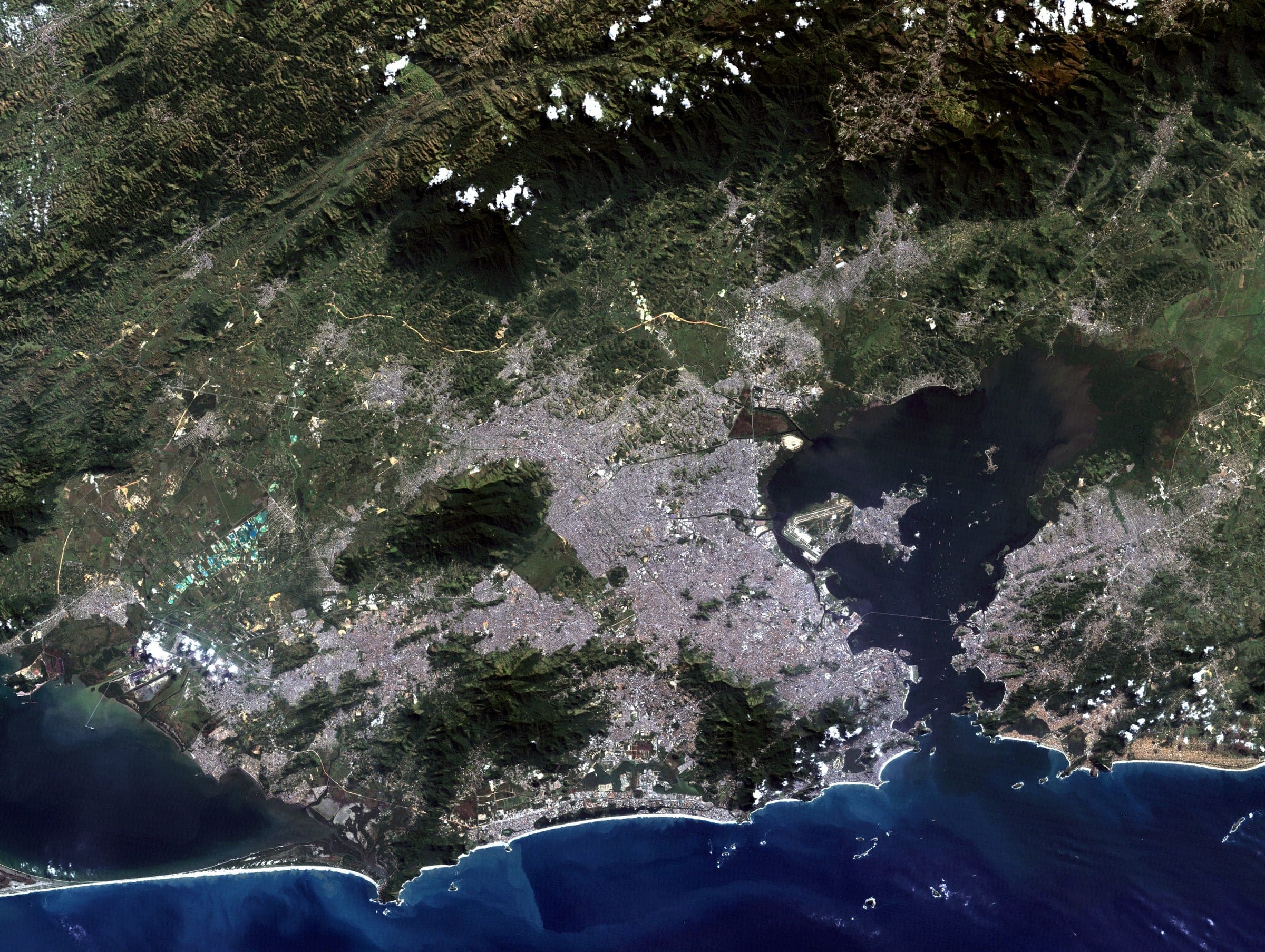 Rio de Janeiro built into the gaps between granite massifs, with Guanabara Bay opening north and the lagoons and beaches of the Zona Sul along the Atlantic edge. Landsat frame, 30 metres per pixel.